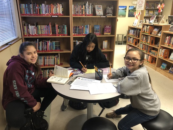 Three kids around a table at the Nooksack after-school homework and reading time